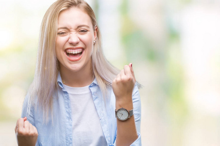 年轻的金发女人在孤立的背景下非常高兴和兴奋做胜利者的手势与手臂