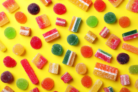 在色彩背景上用美味多彩的糖果平躺构图