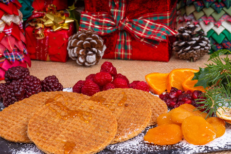 带枫糖浆的华夫饼干. 在石板盘上, 用枫糖浆洒了太妃糖饼干。周围的新鲜和干果的选择圣诞礼物和装饰品