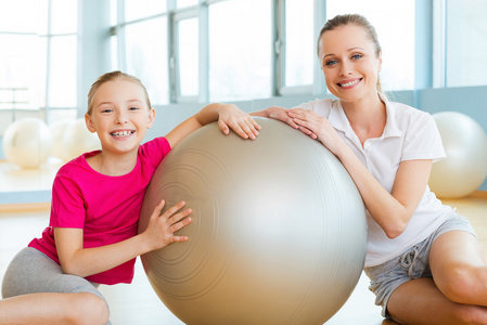 母亲和女儿倚在健身球