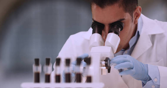 西班牙男性法医科学家通过显微镜检查血液样本
