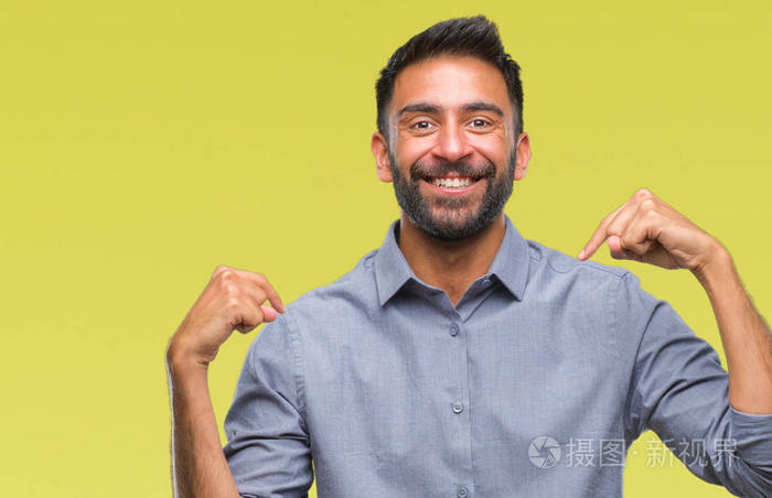 成年西班牙裔男子在孤立的背景下, 脸上露出自信的笑容, 用手指自豪和