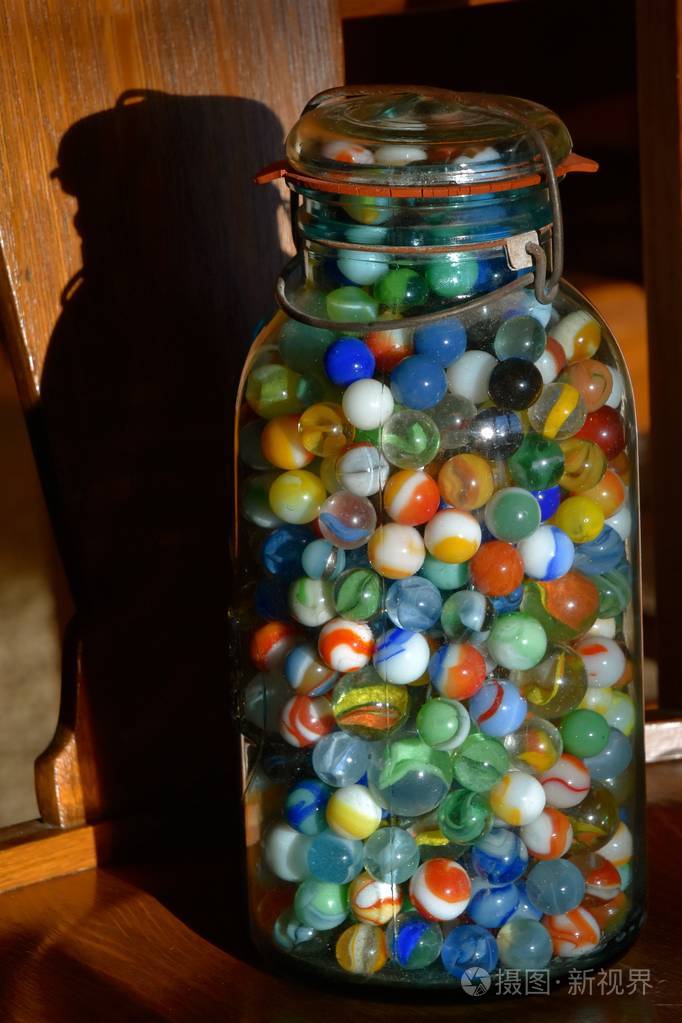 一罐玻璃弹珠把它的影子扔在椅子的木背景上