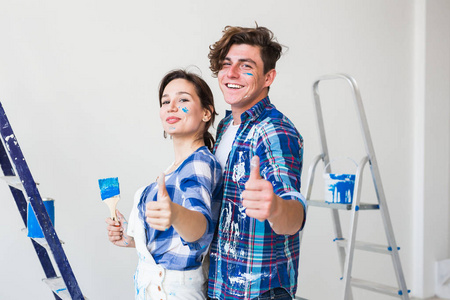 修复翻新和爱情夫妻概念年轻的男人和女人在爱和粉刷墙壁, 露出大拇指