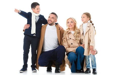 时尚幸福的家庭拥抱与儿童在米色大衣, 男孩显示一些孤立的白色