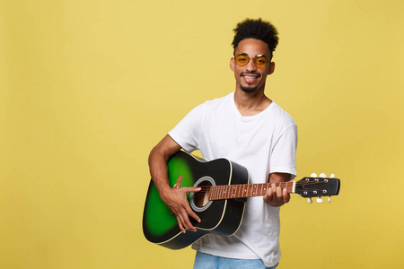 快乐的非洲裔美国音乐家男子摆着吉他, 金色黄色背景