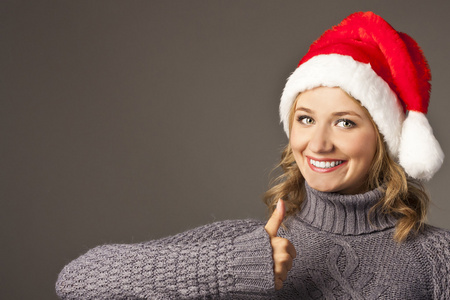 圣诞老人帽子出现拇指的幸福笑脸女孩图片