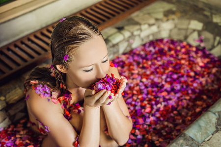 享受热带花卉花瓣和芳香油的温泉浴的年轻妇女