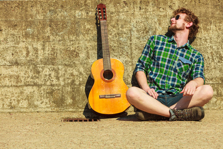 音乐和人们的观念。年轻人用室外街上的吉他有胡子的时髦人