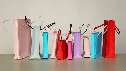 一排不同颜色的购物袋, 上面有白色的背景。销售, 礼品, 节假日。美与时尚理念