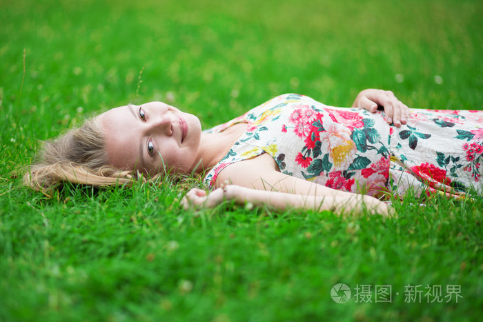美丽的年轻女孩躺在草地上