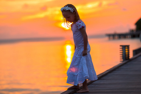 可爱的小女孩，在木码头在日落时的剪影