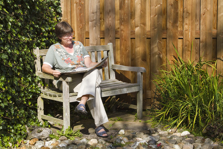在森林里坐在板凳上小男孩和小女孩在阳光灿烂的夏天一天坐在板凳上