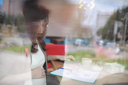 在咖啡馆工作的怀孕妇女在计算机