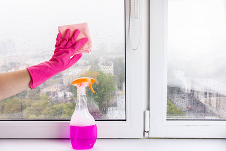 一只女手用抹布冲洗窗台和窗户。