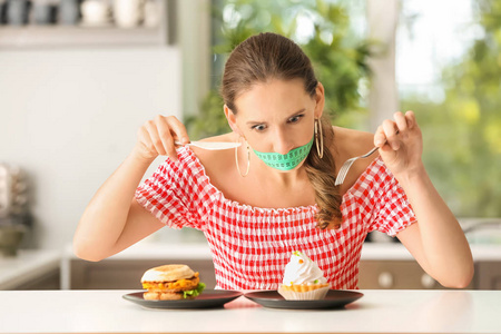 情绪化的女人, 她的嘴巴周围有卷尺, 厨房里不健康的食物。饮食理念