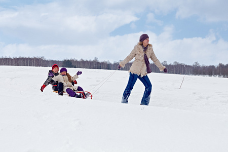 儿童雪橇骑马帮助他们的母亲