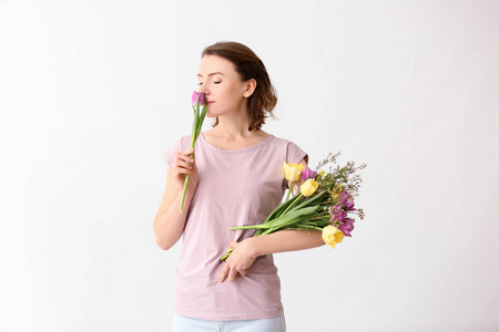 美丽的女人与花束的花朵在光的背景下