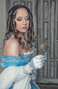 美丽的中世纪女人，穿着蓝色的衣服，用镜子