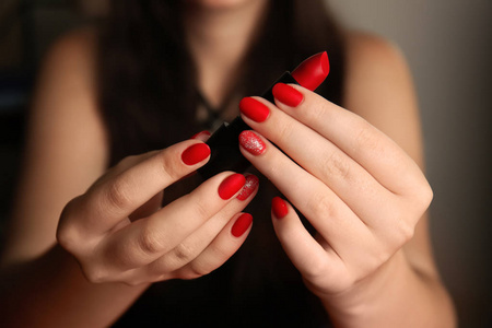 女人与时尚的红色指甲持有口红, 特写