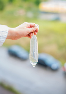 女人的手控股避孕套装满了水.复仇的概念照片