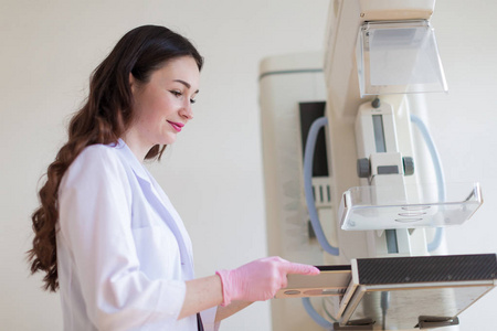 年轻快乐乳房专家的侧面视图在粉红色的手套谁正在准备乳房超声检查仪在她的办公室进行超声检查