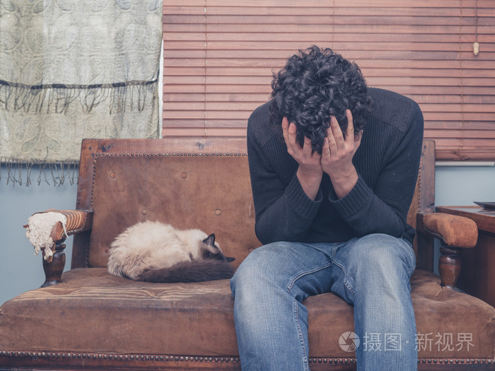 猫在沙发上难过和沮丧的年轻人