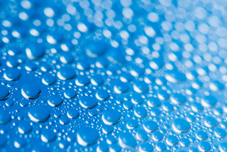 蓝色玻璃背景下的雨滴。浅景深的软聚焦宏射击