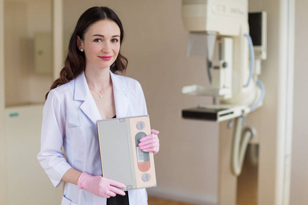 年轻开朗乳房专家的肖像在粉红色的手套站在她的办公室乳房超声检查设备附近