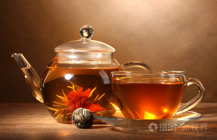 玻璃茶壶和异国情调绿茶棕色 backgro 上的木桌上的杯子