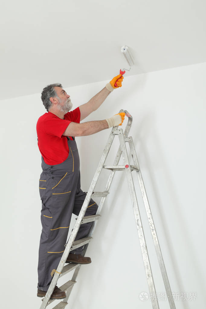 从梯子油漆滚筒工人画天花板