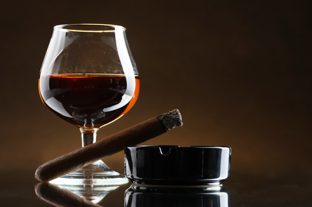 杯白兰地酒和雪茄棕色背景上
