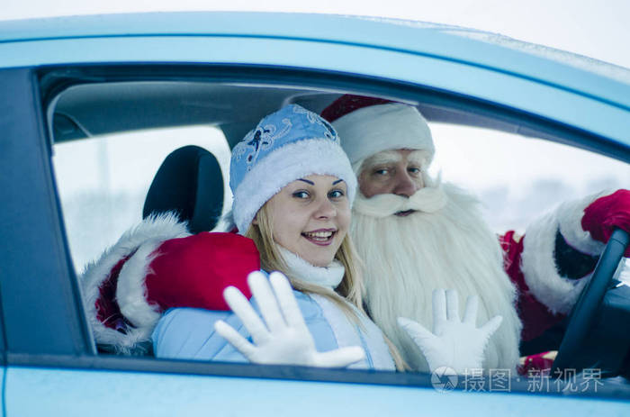 滑稽的圣诞老人和他的美丽的孙女坐在车里