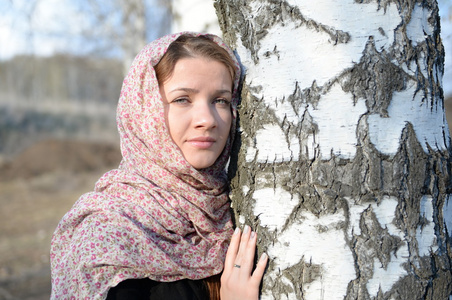 俄罗斯姑娘在一条围巾在白桦林关闭