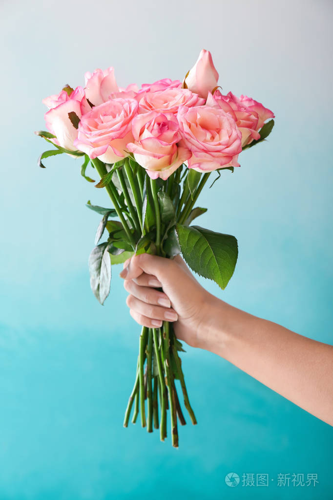 在色彩背景上捧着美丽玫瑰花的女人