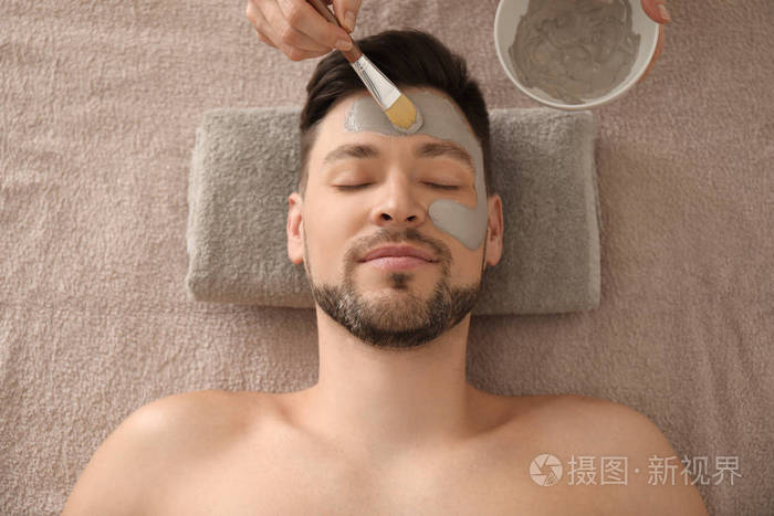 美容师在水疗沙龙男士脸上涂抹化妆面具