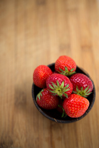 在一个木制的背景上的木碗中的新鲜草莓