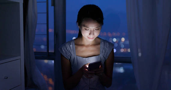 在夜间使用智能手机的女人