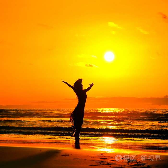 夏日夕阳光在海滩上的年轻女子剪影