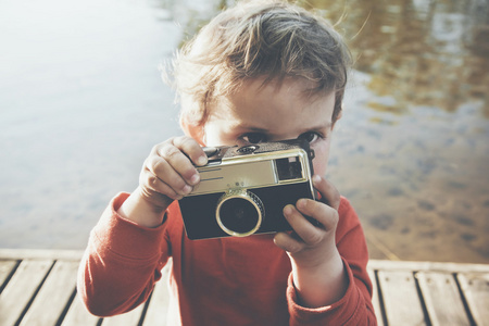 微笑的可爱男孩拍照与复古相机的肖像