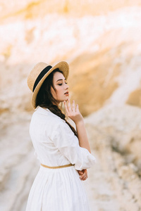 迷人的女孩摆在时髦的礼服和草帽在沙峡谷