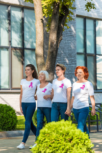 快乐的妇女与乳腺癌意识丝带牵手, 走在一起