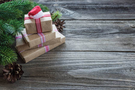 圣诞节组成的松果，云杉分行和堆栈的礼品盒用背景上圣诞老人的帽子的老未上漆的木板上与复制空间