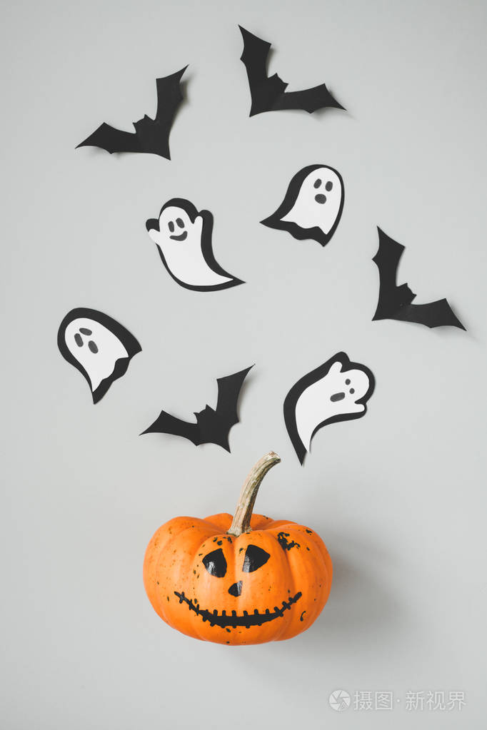 万圣节快乐滑稽的万圣节南瓜与纸蝙蝠和幽灵在灰色背景下
