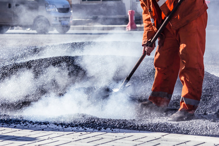 工人用铁锹在道路施工沥青