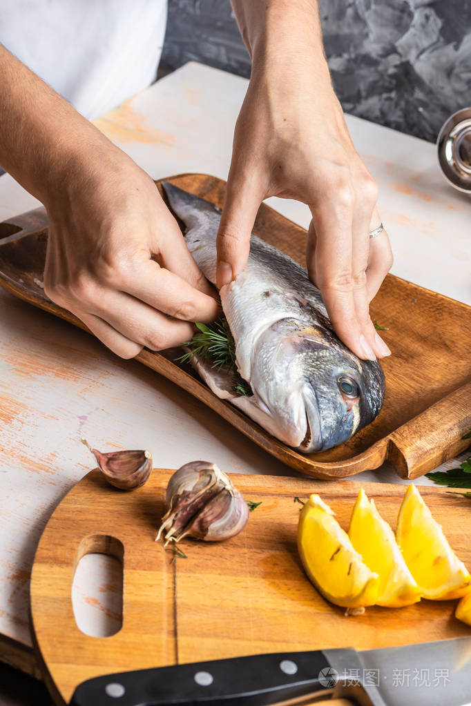 用柠檬橄榄油和草药烹调金鱼的过程女性手特写自制食品概念烹饪嗜好