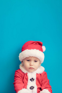 悲伤的孩子的肖像。滑稽的孩子穿着圣诞老人的服装。圣诞假期概念