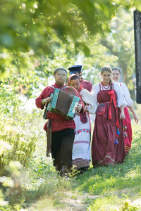 一群身着俄罗斯民俗服饰的人围着一个美丽的村庄散步。