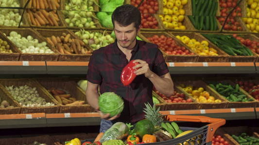 男人把不同的蔬菜放进购物车里