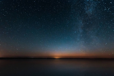 蓝夜星空与银河银河以上湖和俄罗斯村。夜晚发光的星星